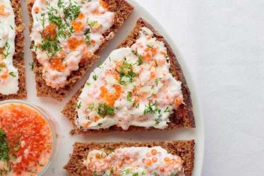 Homemade appetizer with red caviar, sour cream, dill, onion and rye bread on the white table - the traditional finnish recipe for a holiday food, flat lay in minimalistic style, healthy eating concept, horizontal