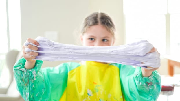 In a modern kitchen, a homeschooled girl is engrossed in creating homemade slime, a fun and educational hands-on project that enhances her creativity and problem-solving skills.