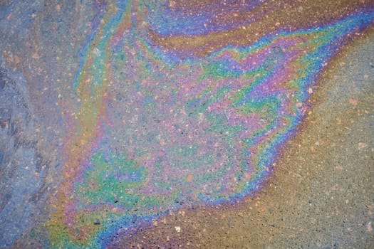 An oily iridescent stain of gasoline or oil spilled on the road