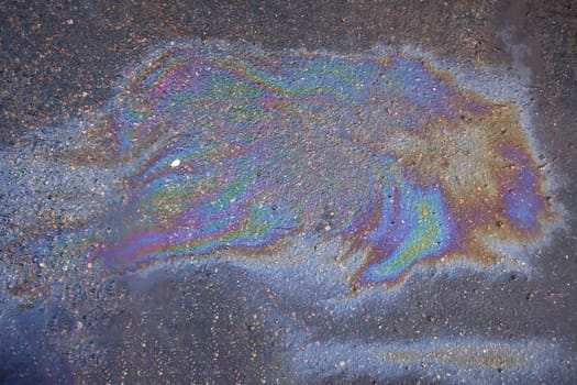 Textured stain of fuel or oil on wet asphalt on a rainy day.