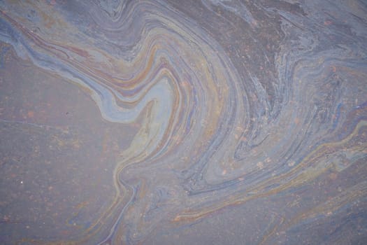 A marble texture of a rainbow spill of gasoline on a sidewalk in a puddle as a background.