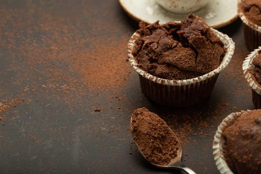 Chocolate and cocoa browny muffins with coffee cappuccino in cup angle view on brown rustic stone background, sweet homemade dark chocolate cupcakes, space for text.