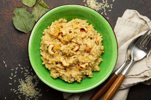 Ven Pongal (Khara Pongal), traditional Indian savoury rice dish made during celebrating Pongal festival, served in bowl top view on concrete rustic background.