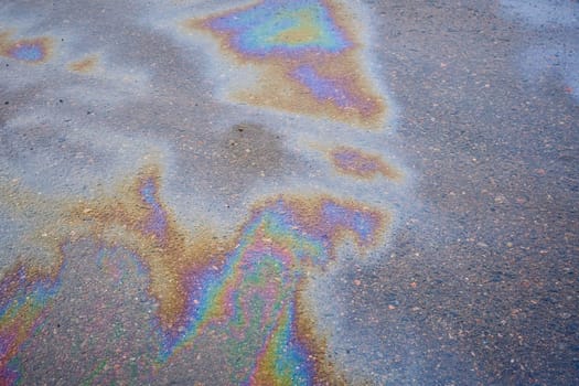 Petroleum fuel spilled on wet asphalt, abstract background. Selective focus