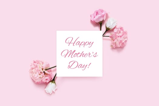 Happy mother's day picture. Pink background with sheet of white paper and flowers.