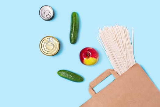 Contactless set of finished product kit. Flat lay with grocery bag on blue background.