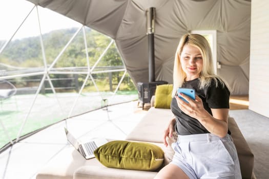 woman with smartphone in geo dome tent.