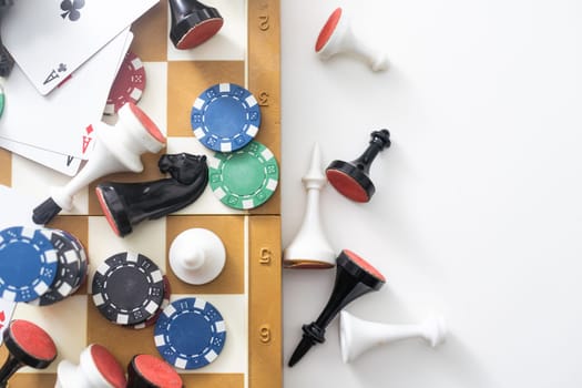 Wooden checkers, chess pieces, playing cards, board games on a light table close up