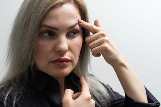 woman shows drooping eyelid for plastic surgery.