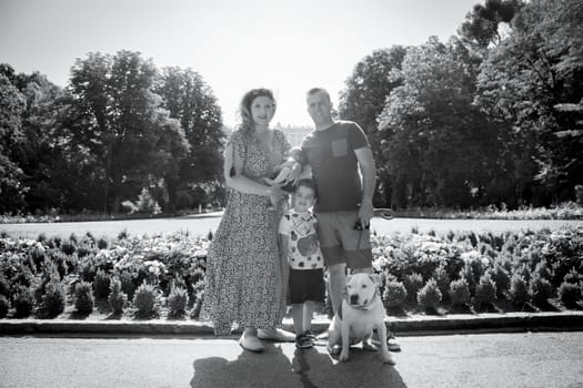 Family posing standing composed of parents, two children and a dog. Summer day.