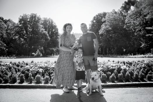 Family posing standing composed of parents, two children and a dog. Summer day.