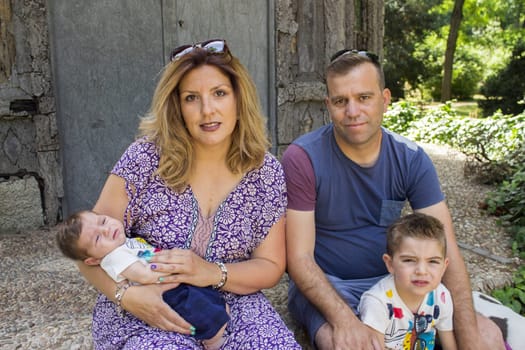 Family consisting of parents and two children. Sitting on some stairs.