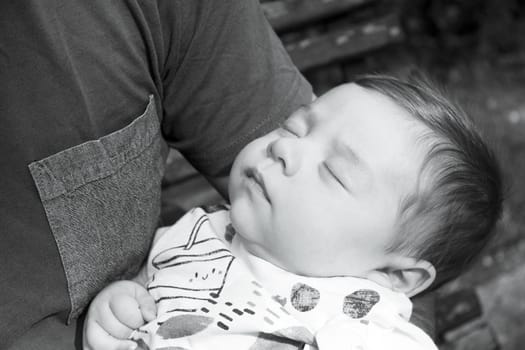 Baby sleeping in his fathers arms. Sweet scene