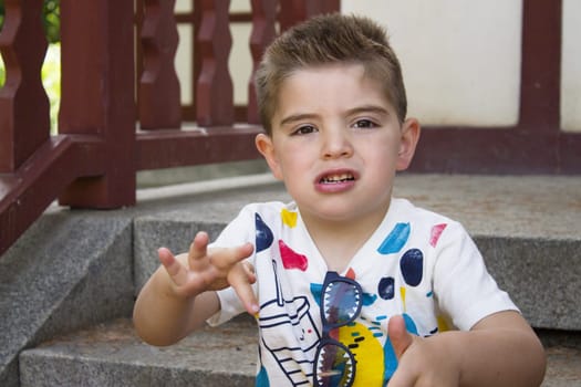 Four year old boy sitting gesturing. Alone