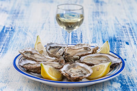 Oysters and glass of white wine in a restaurant wooden table background