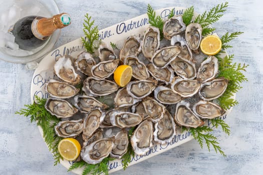 Oysters and white wine in a restaurant on blue wooden background