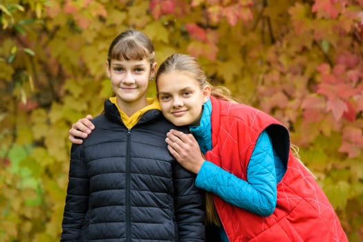 Portrait of two girls of Slavic appearance in casual autumn clothes against the background of an autumn forest a