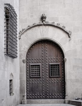 Wooden door with iron fittings in Gothic Quarter street in Catalonia. A medieval door of wood in a stone wall. Typical architecture of medieval Europe. High quality picture for wallpaper, article