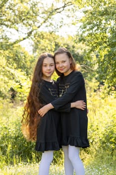 Siblings Day Two Children, Sisters Smile and Hug . Green Trees, Park on Background. Love. Joyful Carefree Girls Lifestyle Childhood. Horizontal. Brothers and Sisters Day. Vertical.