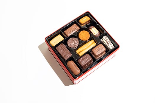 Isolated Assorted shortbread Belgian Cookie in Red Box on White Background. Festive holiday Dessert Assortment. Flat lay 12 Sections feature delicious treats like Christmas Biscuits. Horizontal Plane.