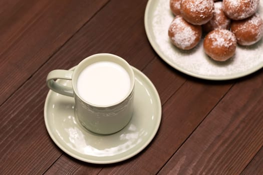 Top View Cup Of Milk, Zeppole Or Paczki On Plate With Powdered Sugar On Wooden Table. Fat Thursday Carnival or Tlusty Czwartek, Christian tradition. Doughnut, Delicious Donuts. Horizontal Plane.