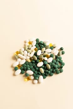 Assorted Pile of Colorful Pills, Green White Yellow, Beige Tablets, Capsules, Medical Supplement on Beige Background. Pharmaceutical concept. Copy Space For Text. Vertical Plane. High quality photo