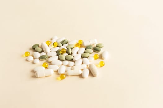 Assorted Pile of Colorful Pills, Green White Yellow, Beige Tablets, Capsules, Medical Supplement on Beige Background. Pharmaceutical concept. Copy Space For Text. Horizontal Plane. High quality photo