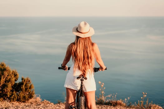 A woman cyclist on a mountain bike looking at the landscape sea. Adventure travel on bike