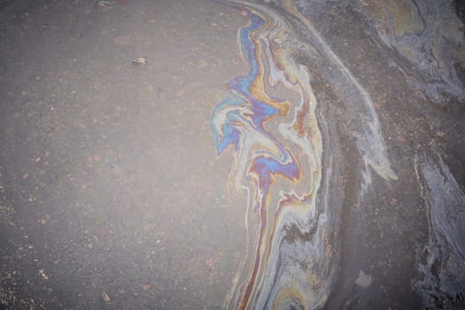 Dirty multi-colored stain from engine oil on asphalt. Environmental pollution concept.