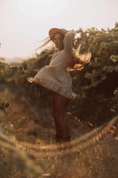 Woman with straw hat stands in front of vineyard. She is wearing a light dress and posing for a photo. Travel concept to different countries.