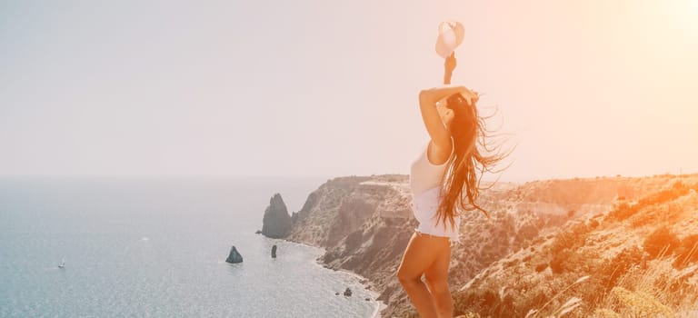 Woman travel sea. Young Happy woman in a long red dress posing on a beach near the sea on background of volcanic rocks, like in Iceland, sharing travel adventure journey