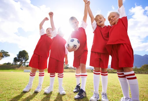 Children, soccer team and celebration for winning or victory, happy and success in outdoors. People, kids and fist pump for achievement, collaboration and partnership or teamwork on field or sport.