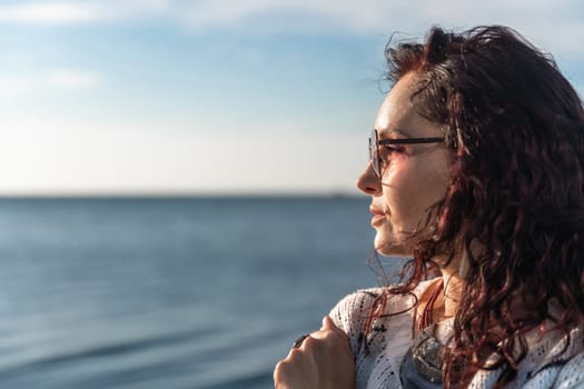 Portrait of a curly woman in glasses on the background of the sea. Vacation on the sea, walk, tourism