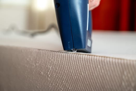 Worker stapling sofa lining with electric staple gun