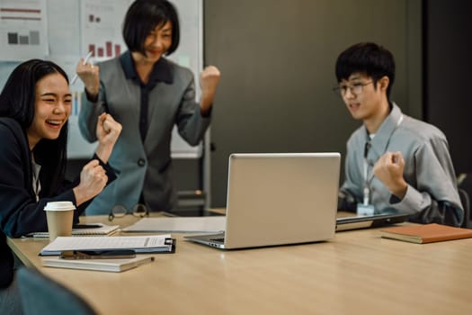 Excited happy business people celebrating corporate achievement at meeting room