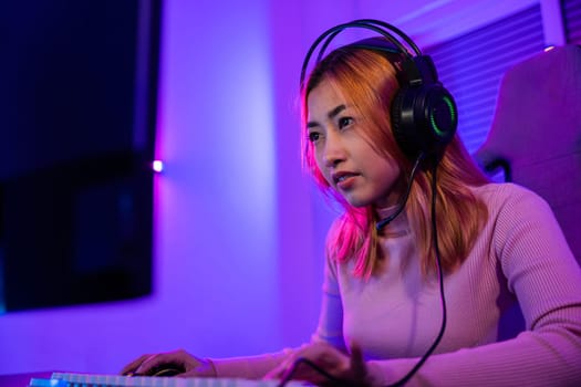 Young player woman wearing gaming headphones intend to do playing live stream games online at home, Happy Gamer endeavor plays online video games tournament with computer desktop with neon lights