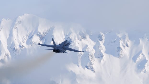 Meiringen Switzerland January 19 2023: Silhouette of fighter jet plane in flight. Snow capped mountains background on a sunny winter day. Copy Space. Boeing F-18 Hornet of Swiss Air Force WEF security