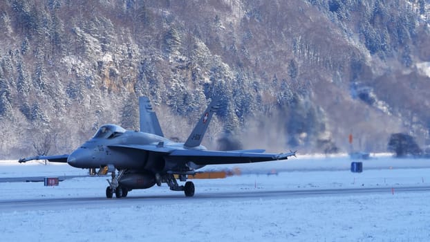 Meiringen Switzerland January 19 2023: Fighter jet taxiing in white winter snow scenario. Copy Space. Boeing F-18 Hornet of Swiss Air Force air defense for World Economic Forum WEF in Davos.