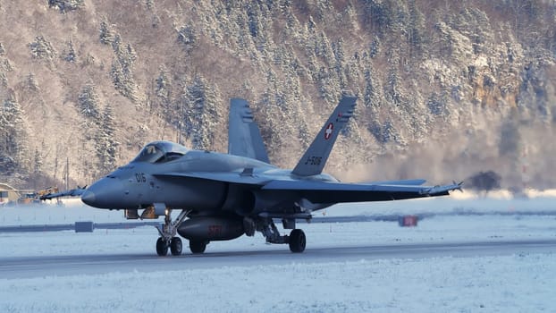 Meiringen Switzerland January 19 2023: Fighter jet taxiing in white winter snow scenario. Copy Space. Boeing F-18 Hornet of Swiss Air Force air defense for World Economic Forum WEF in Davos.