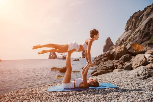 Woman sea yoga. Back view of free calm happy satisfied woman with long hair standing on top rock with yoga position against of sky by the sea. Healthy lifestyle outdoors in nature, fitness concept.