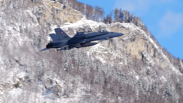 Meiringen Switzerland January 19 2023: Armed fighter jet taking off with white snow capped mountains background. Copy Space. F-18 Hornet of Swiss Air Force for Davos World Economic Forum WEF