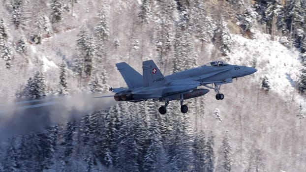 Meiringen Switzerland January 19 2023: Armed fighter jet provide air defense during the World Economic Forum WEF in Davos. Copy Space. Boeing F-18 Hornet of Swiss Air Force. White winter snow scenario