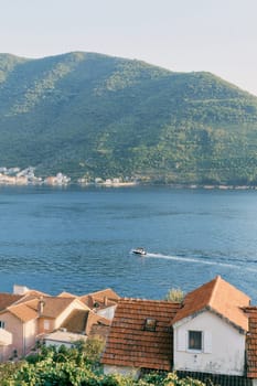 View over the red tiled roofs of the houses to a boat sailing on the bay. High quality photo