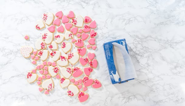 Denver, Colorado, USA-February 9, 2023-Flat lay. Storing heart-shaped sugar cookies with pink and white royal icing in a large plastic container.