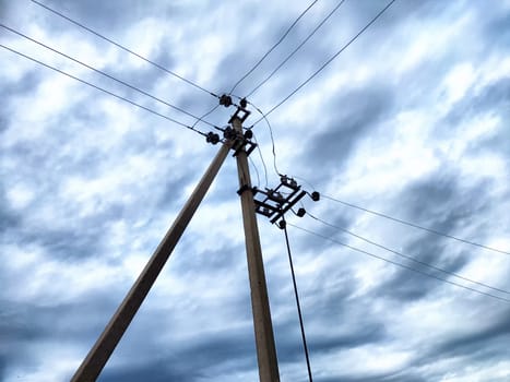 Old power poles and the sky with clouds in the background. Electric lines, towers, wires in landscape
