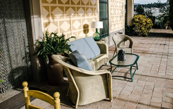 Dining coffee table with chairs on tile floor exterior. Living area in countryside house or hotel. Beautiful urban architectural photography. High quality picture for wallpaper, article