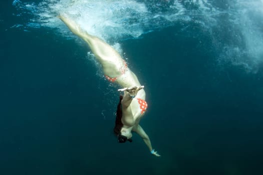 beautiful bikini girl diving in the deep blue sea