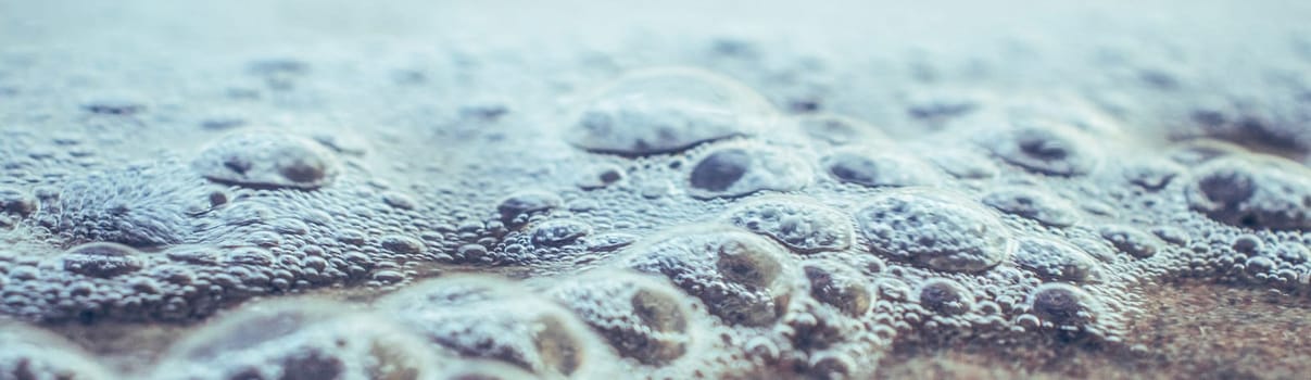 Close up sea water with little bubbles photo. Surface with selective focus in the foreground and blurry background. Mediterranean sea, nautical background. High quality picture for wallpaper, travel blog