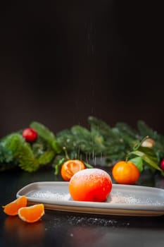 Plate with delicious mochi and tangerine on a dark Christmas background. High quality photo