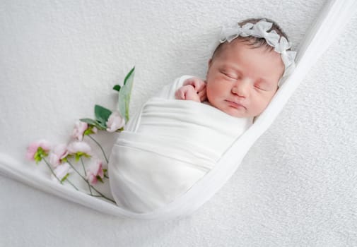 Newborn Girl Sleeping On A Bib In White Tones During A Baby Photo Session In Studio